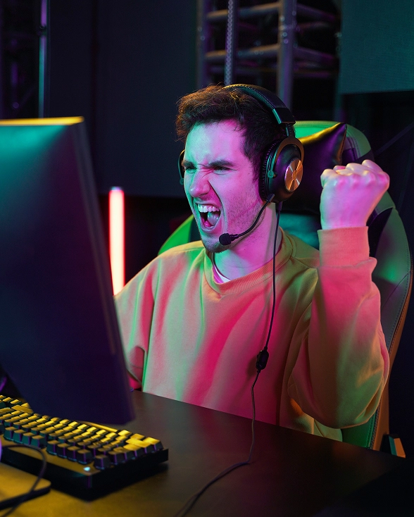 Giocatore con cuffie festeggia una vittoria durante una sessione di gaming al computer